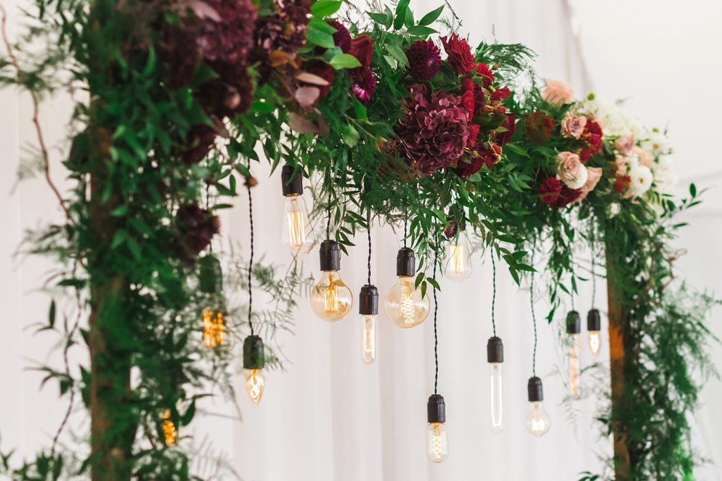 Wedding reception decoration with different electric edison lamps and fresh red and bordo flowers, rustic style Wedding reception decoration with different electric edison lamps and fresh red and bordo flowers, rustic style